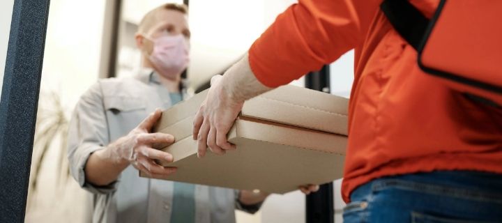 Image of a food delivery person handing packaged food to a customer